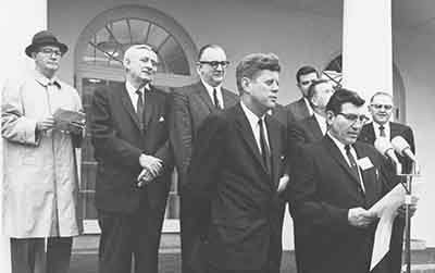 Congressman Haley and President Kennedy stand in a group as an announcement is made.