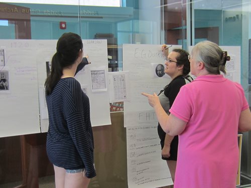 Two students reviewing documents with the college archivist, gerrianne schaad