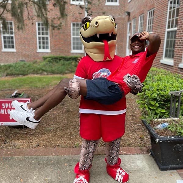 Mocsie carrying a student outside a dorm building